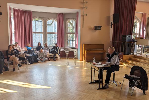 Schüler*innen der Berufsschule im PFH hören Winfried Schweitzer beim Erzählen seiner Geschichten zu.